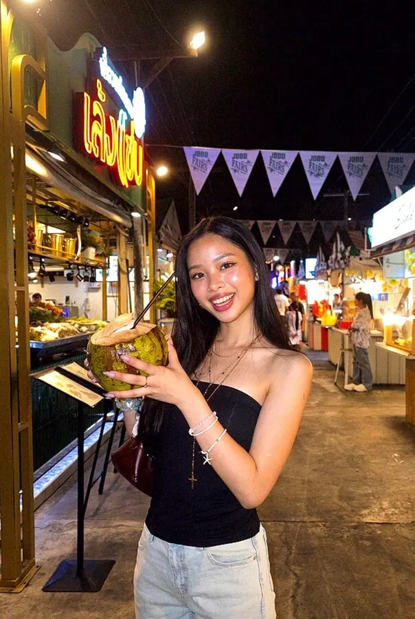 Y2K Digicam look: the same night-market photo lit by a compact camera's flash, her face bright and the market a little darker
